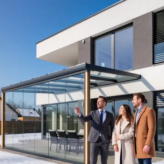 Риелтор показывает современный дом с прозрачным обогреваемым козырьком потенциальным покупателям в солнечный зимний день