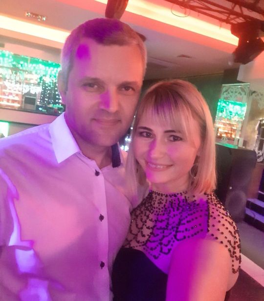 фото мужа и жены с улыбкой на лицах в лучах фиолетовых огней 