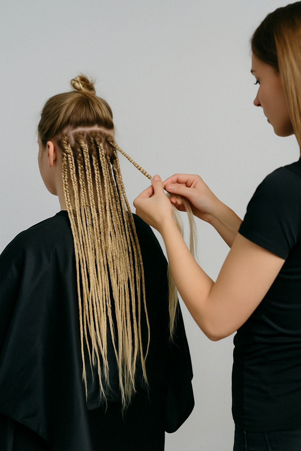 Процесс точечного вплетения зизи-косичек в пряди натуральных волос — мастер работает с затылочной зоной